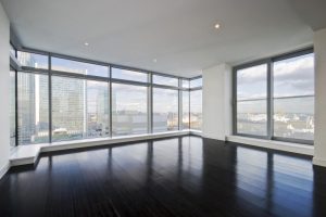 Empty apartment with hard wood floor an floor to ceiling windows