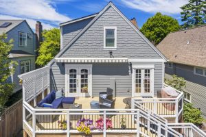 Rear view of Green Lake home and ADU showing new deck, custom railings, arbor, wood shingle siding, and updated exterior finishes.