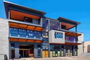 Modern mixed-use building in Ballard, Seattle featuring James Hardie fiber-cement lap and panel siding, extensive glazing, exposed wood soffits, and architectural façade detailing installed by Synapse Construction.