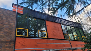 Work-in-progress view of Eastside Prep Middle School exterior in Bellevue showing custom steel panel siding installation and weather-resistive barrier integration.